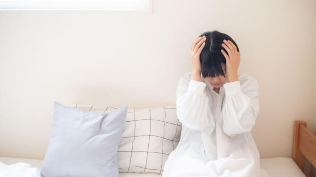 部屋のソファーで頭を抱える若い女性