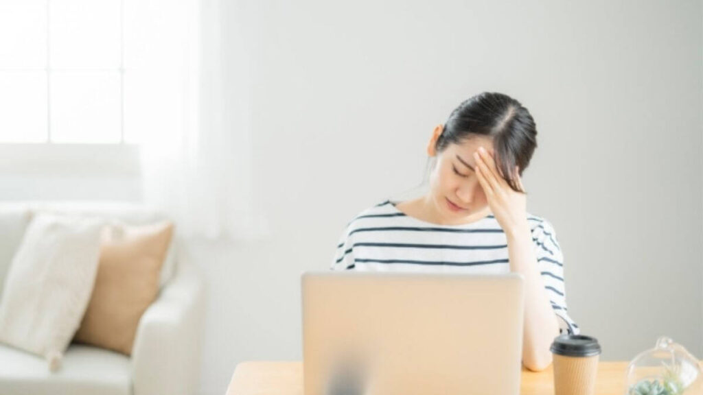 パソコンの前で頭を抱える若い女性
