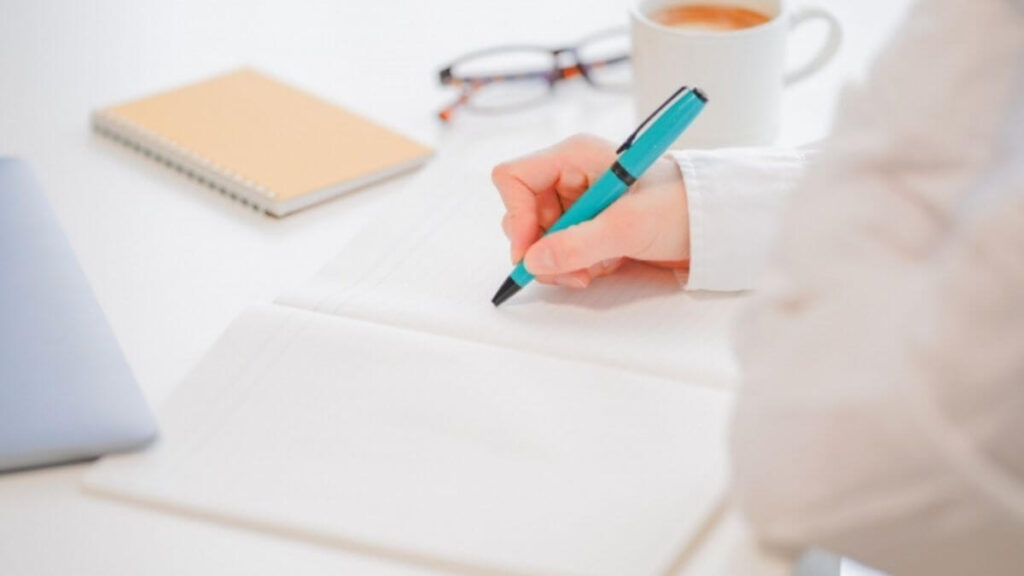 メモ帳に文字を書く若い女性