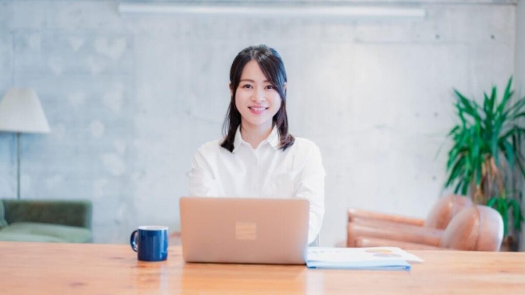 笑顔でパソコンに向い勉強をする若い女性