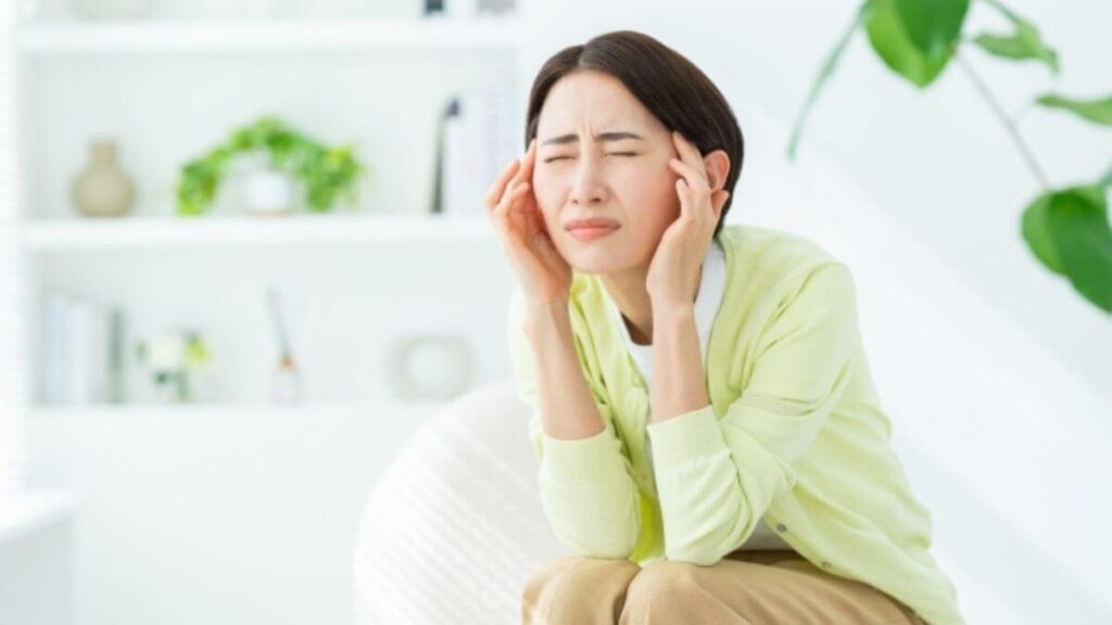 両手で眉間を押さえ悩む主婦
