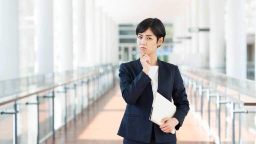 会社の廊下で疑問を感じるスーツ姿の女性