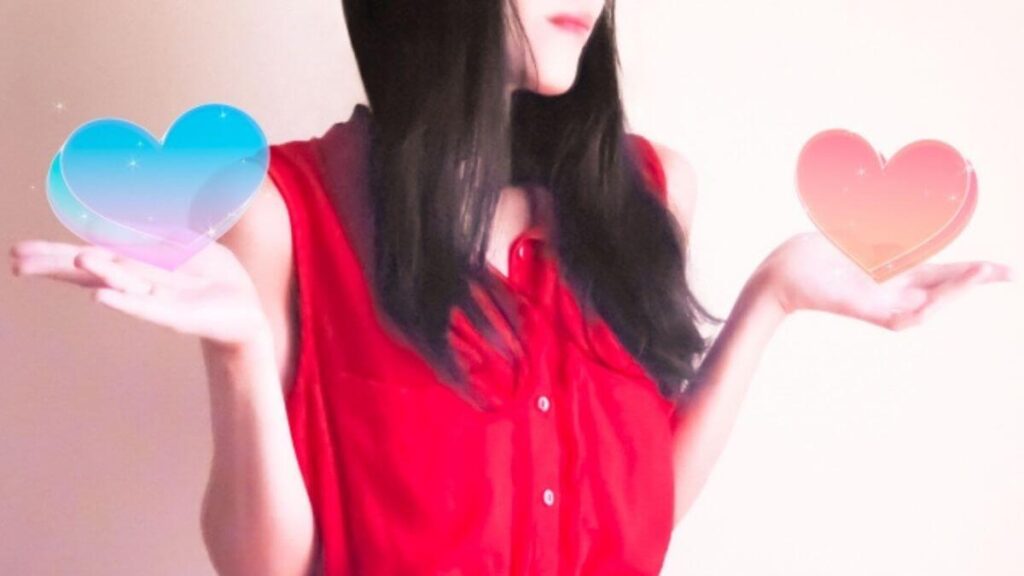 ハートマークを両手に持ち笑顔の若い女性