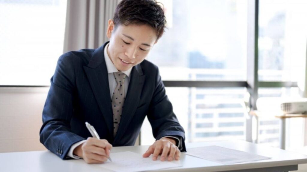 ノートに自分を感情を書きセルフケアを行う男性