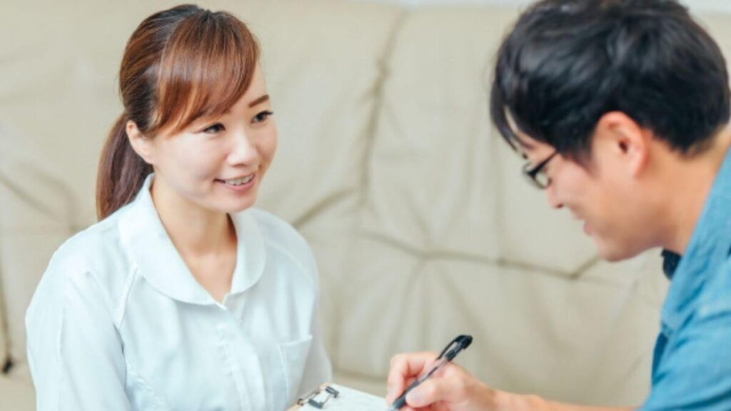 男性相談者の話を笑顔で聞く女性のカウンセラー