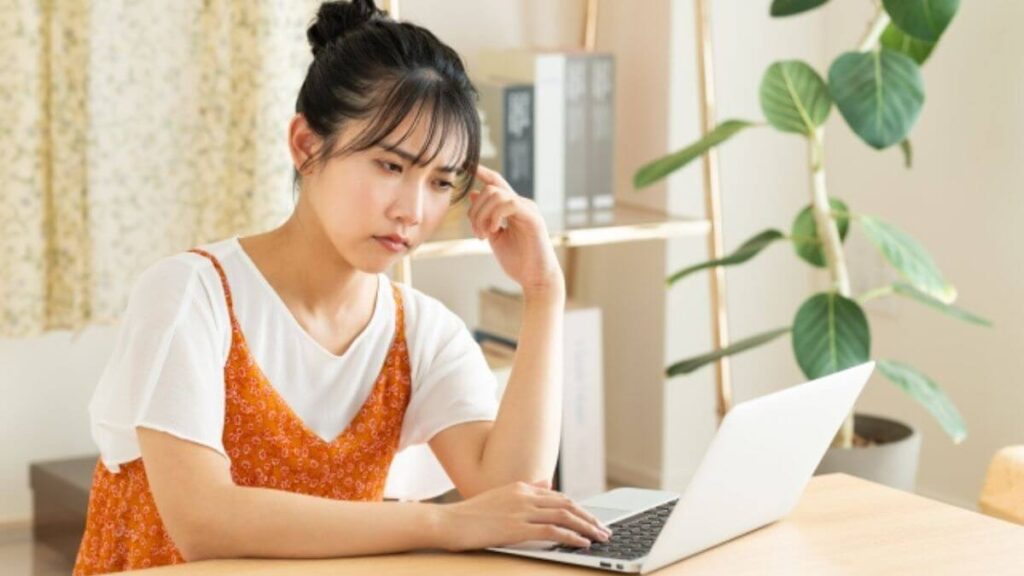 難しい顔でパソコンを操作する若い女性