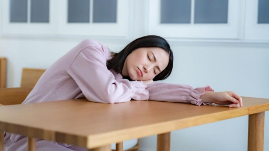 机に伏せて悩む若い女性