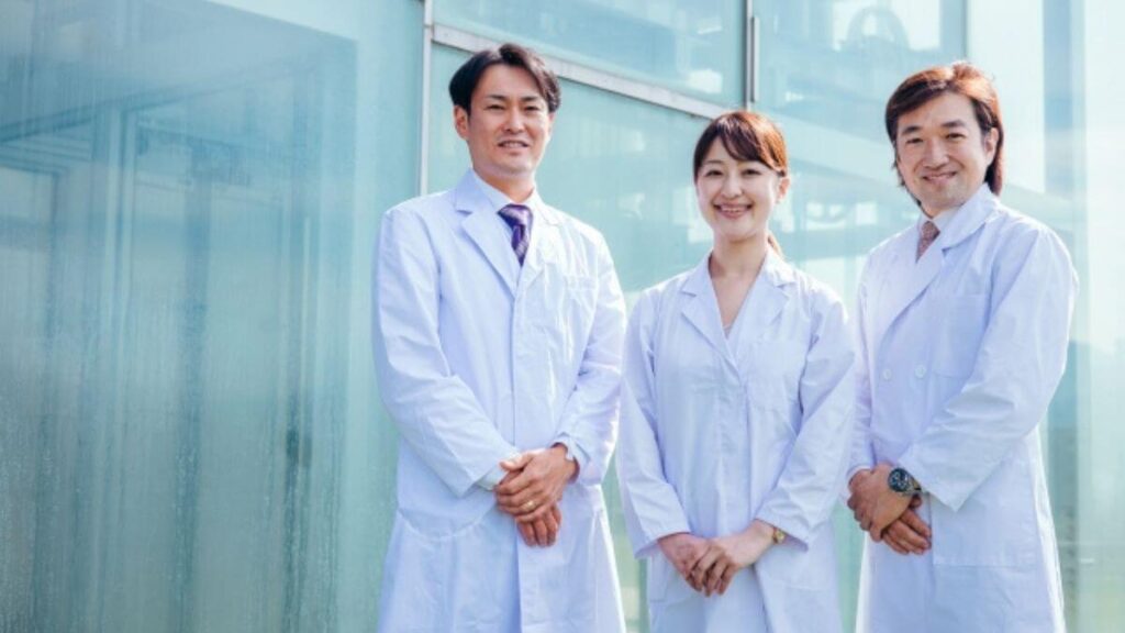 病院前で笑顔で立つ3人の心理カウンセラー