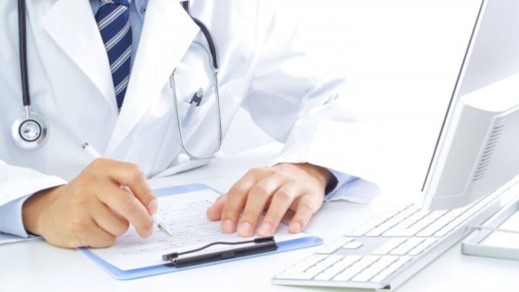 用紙に記入する白衣姿の男性