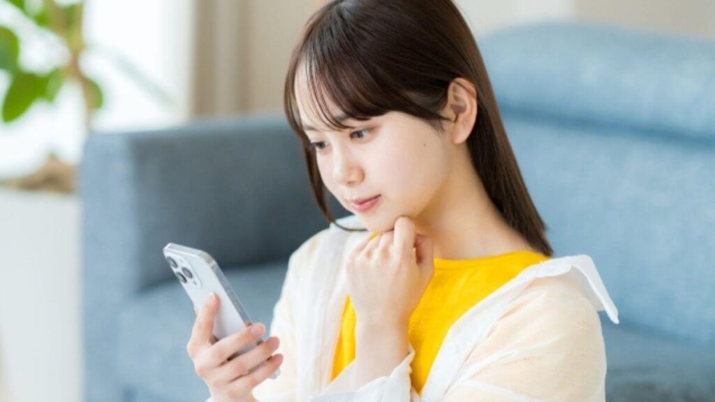スマートフォンを見ながら疑問を感じる若い女性