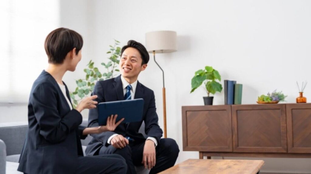 同僚の女性と楽しく会話するスーツ姿の若い男性