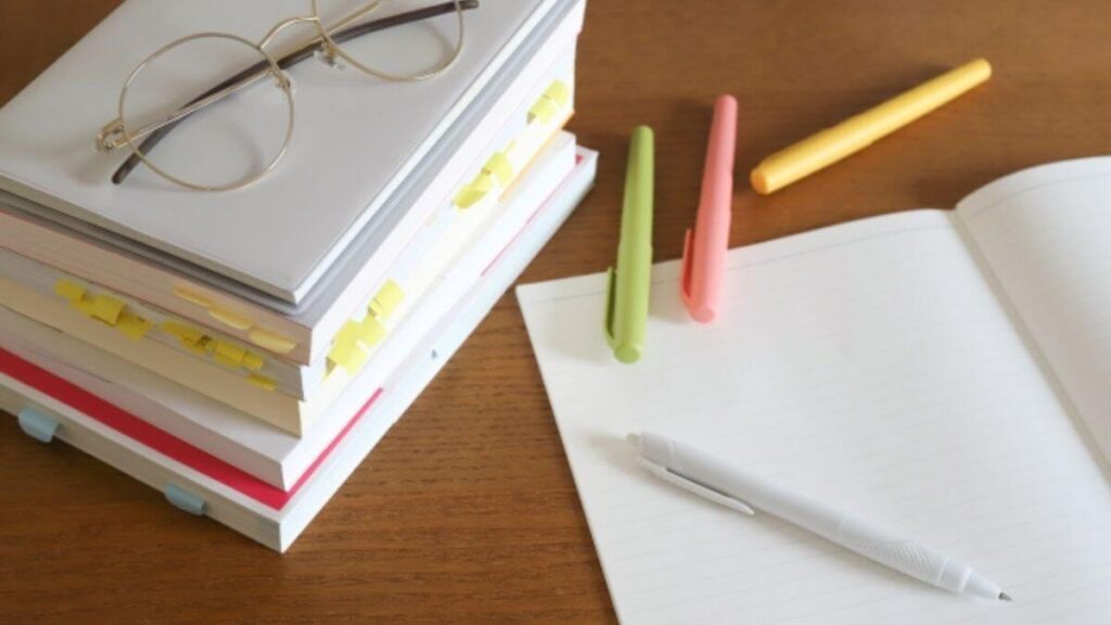 机の上に置かれたノートやペン、参考書