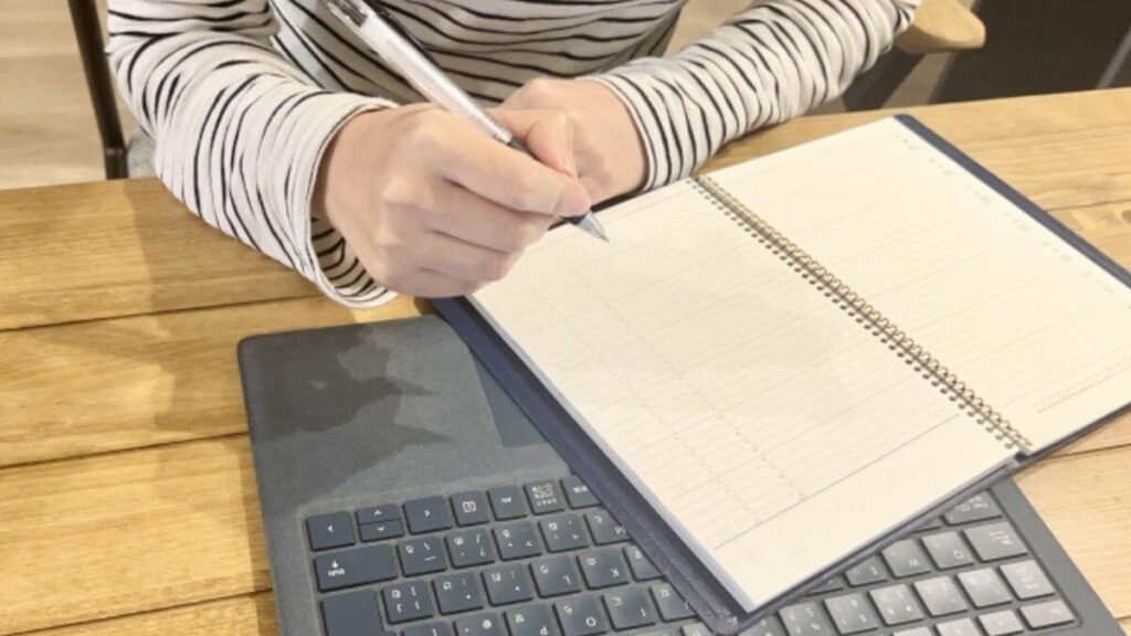 パソコンとノートを使い勉強する女性