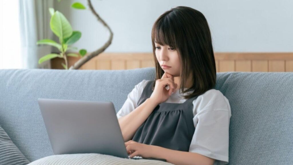 部屋で難しい顔でパソコンを触る女性