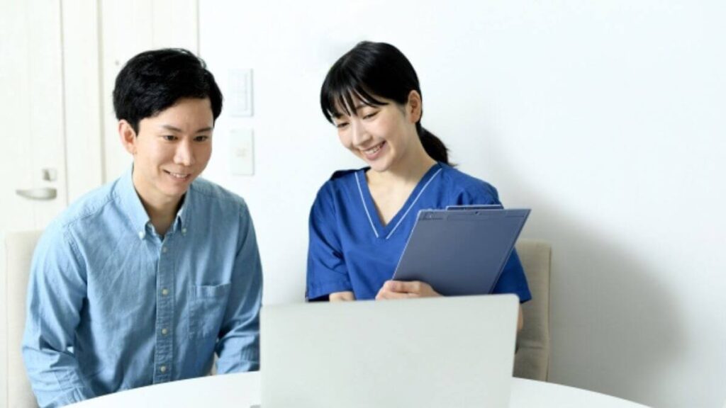 相談者の隣で笑顔で話を聞く女性のカウンセラー