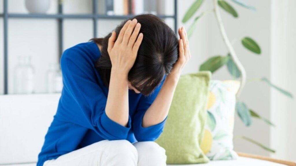 部屋で頭を抱えつらそうにする女性の心理カウンセラー