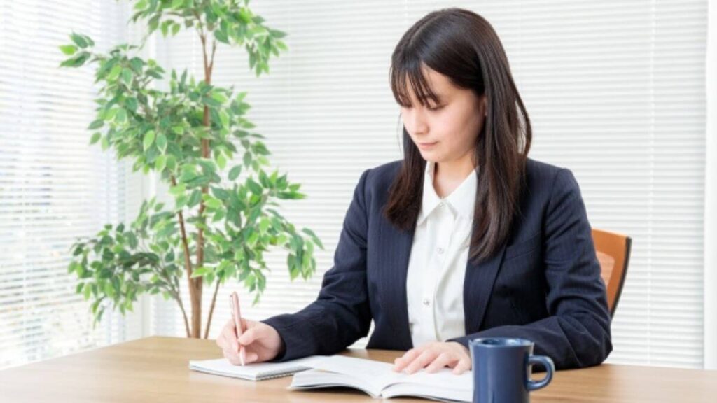 ノートと教科書を使い勉強をする若い女性