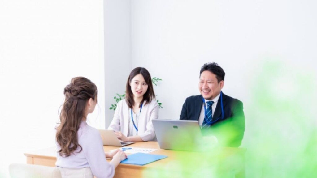 スーツ姿の3人の男女が笑顔で会議する様子