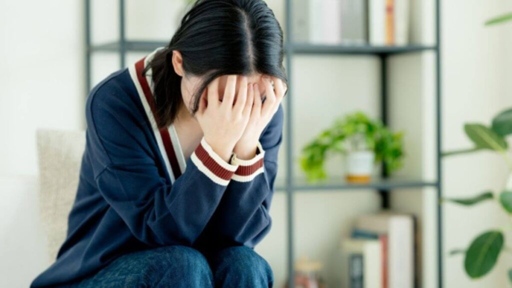 両手で頭を抱えながら落ち込む若い女性