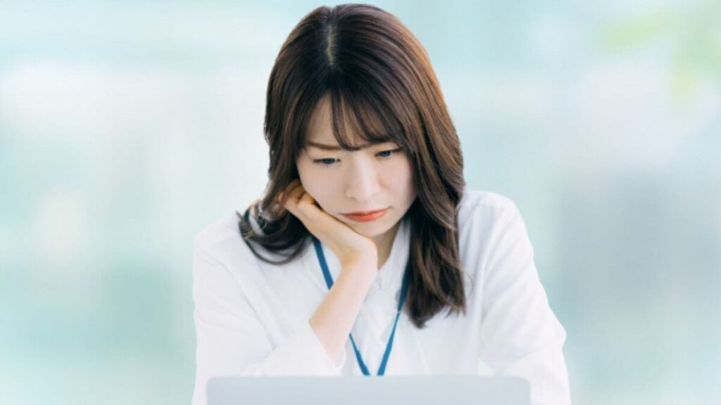 パソコンに向き合い不満そうな表情をする若い女性