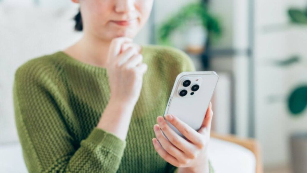 スマートフォンを持ち悩む主婦