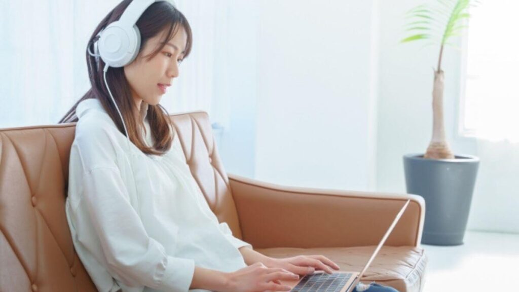 パソコンを使いながら音楽を聞く笑顔の女性