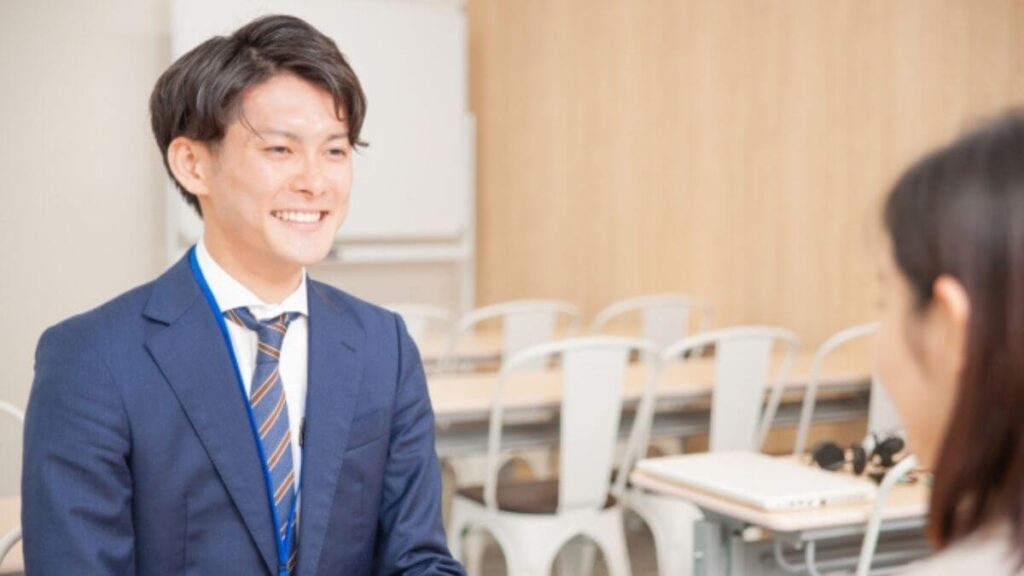 同僚と笑顔で会話をするスーツ姿の若い男性