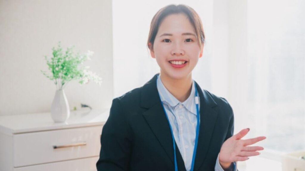 笑顔で手をあげるスーツ姿の若い女性