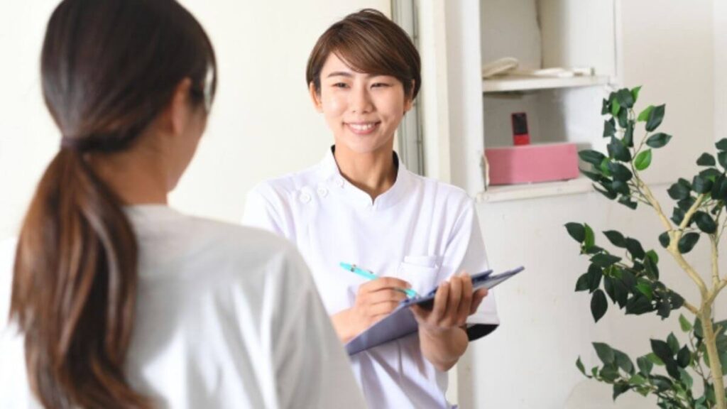 笑顔で相談者の話を聞く白衣姿のカウンセラー