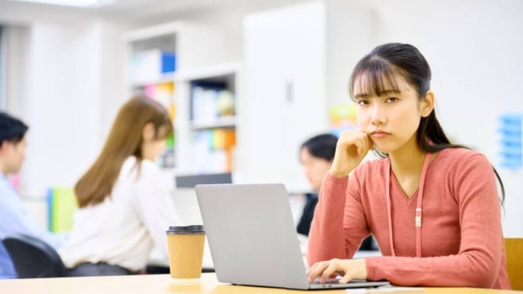 疲れた表情でパソコン作業をする若い女性