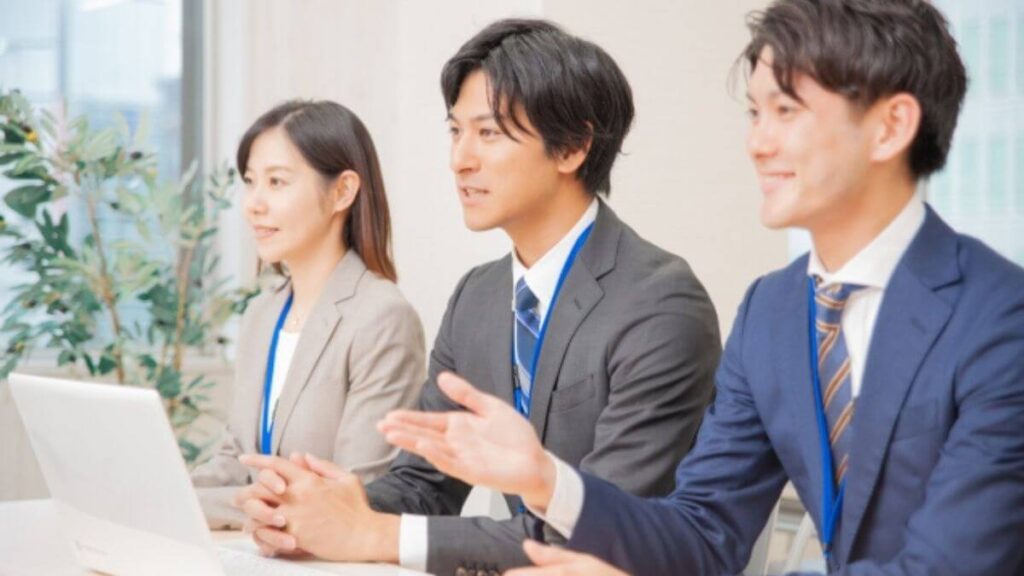 会議で意見を交わすスーツ姿の男女3人