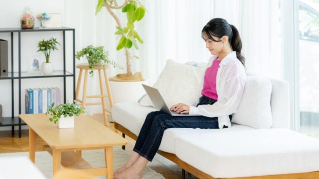 部屋でパソコンを使い勉強する若い女性