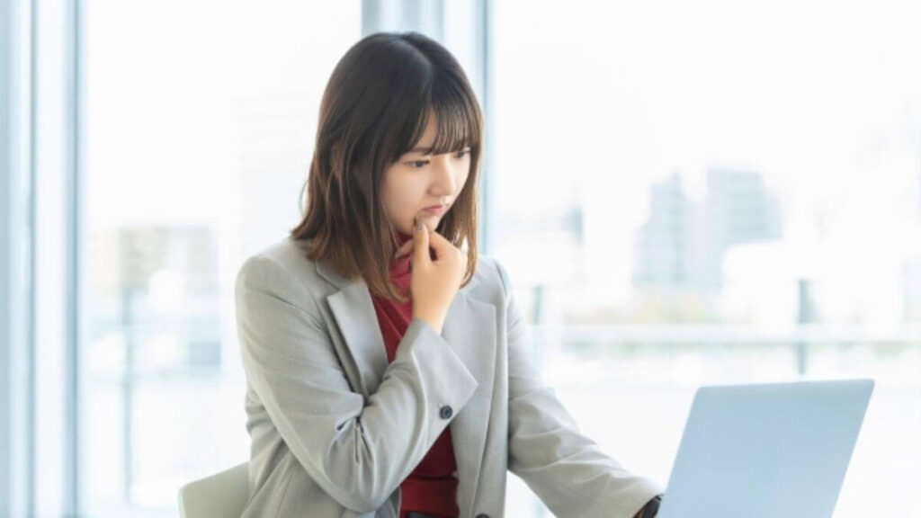 難しい表情でパソコンを使うスーツ姿の女性