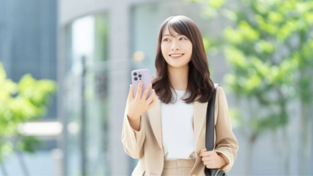 歩きながらスマホを使うスーツ姿の女性