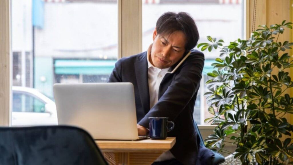 パソコンを使いながら電話をするスーツ姿の男性