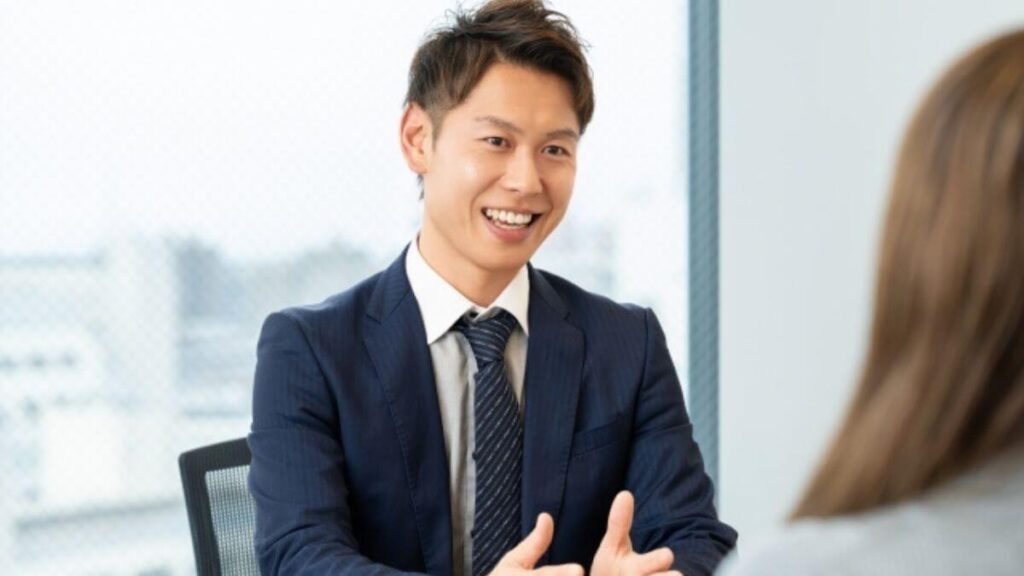 商談中に笑顔で話すスーツ姿の男性