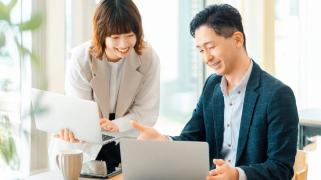 部下の女性に笑顔で説明をするスーツ姿の男性