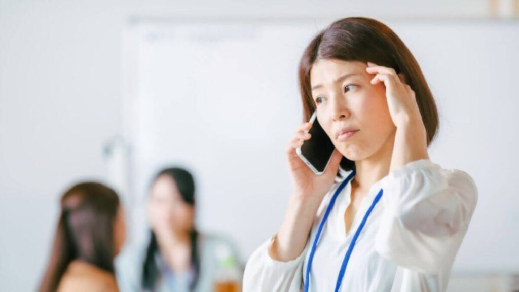 困った顔で電話をするスーツ姿の女性