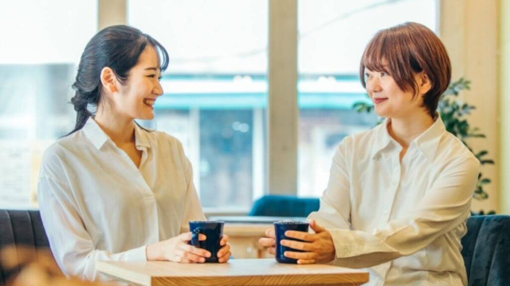 コーヒーを飲みながら会話を楽しむ若い女性2人