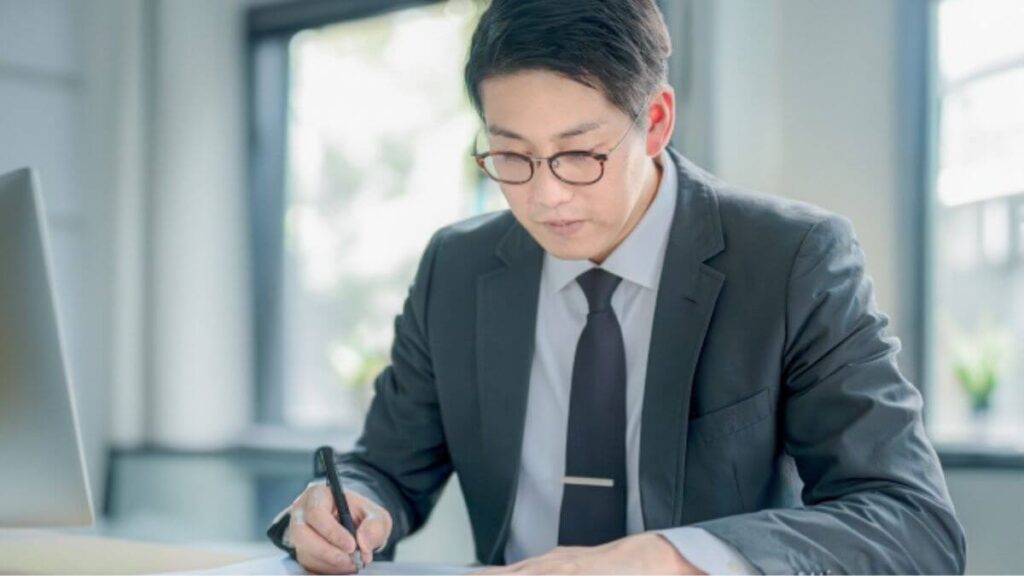 室内でパソコンを使って勉強するスーツの男性