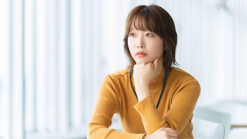 顎に手を置き疑問を感じる若い女性