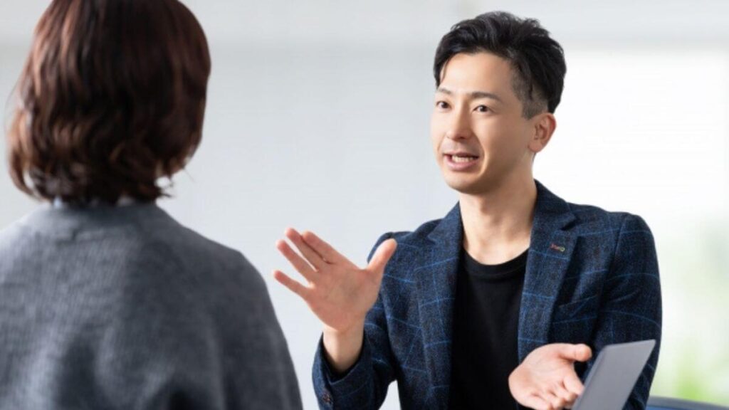 同僚に身振り手振りで丁寧に説明する男性