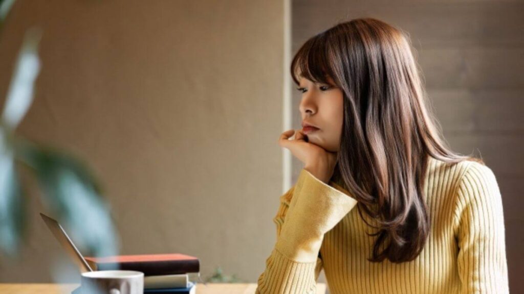 顎に手を置いて悩む若い女性