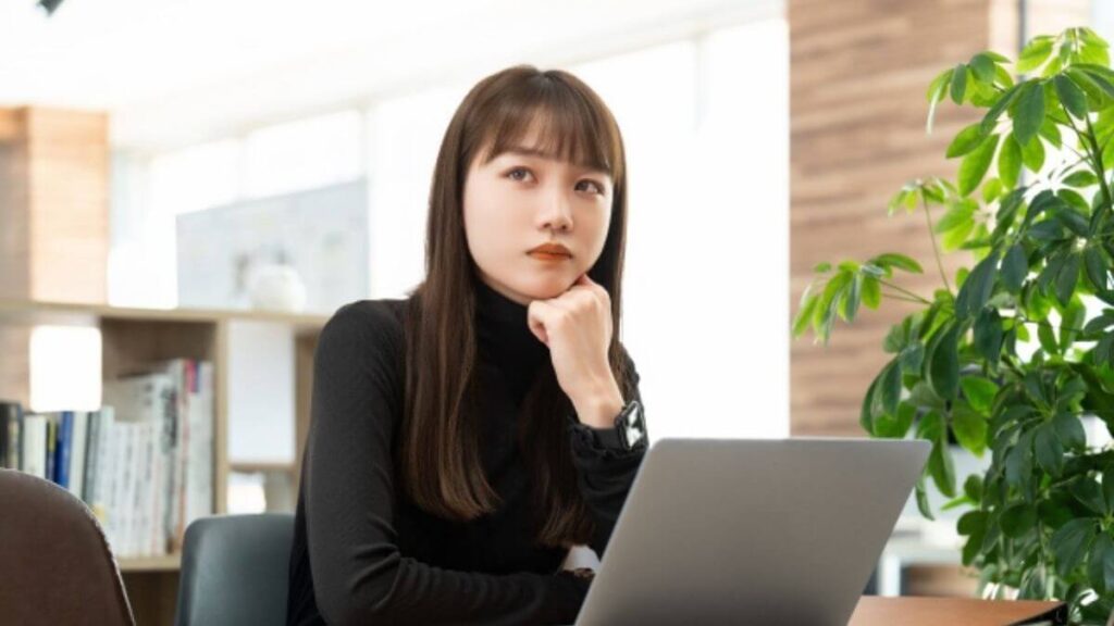 パソコンの前で肘をつき難しい顔をする女性