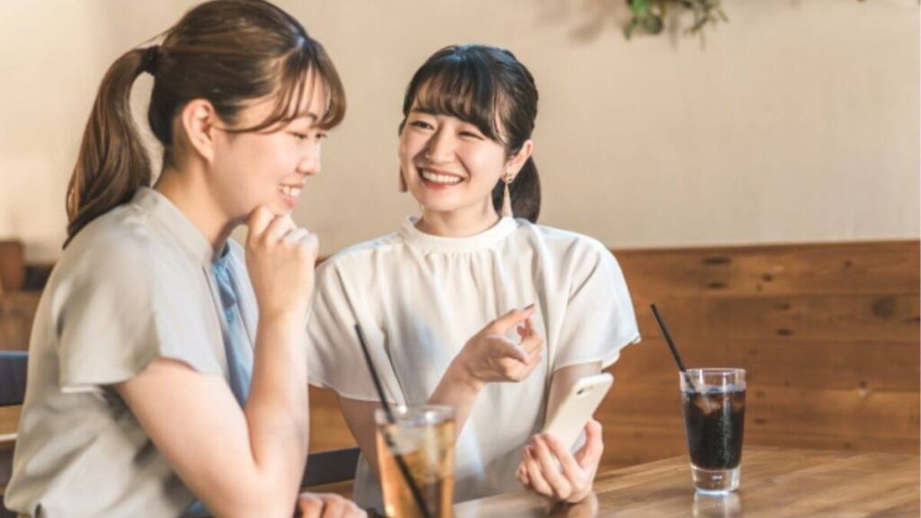 カフェで仲良く会話をする若い女性2人