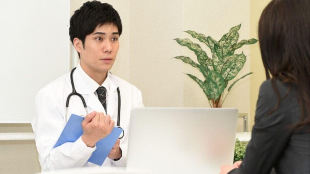 相談者の悩みを真剣に聞く白衣姿の男性カウンセラー