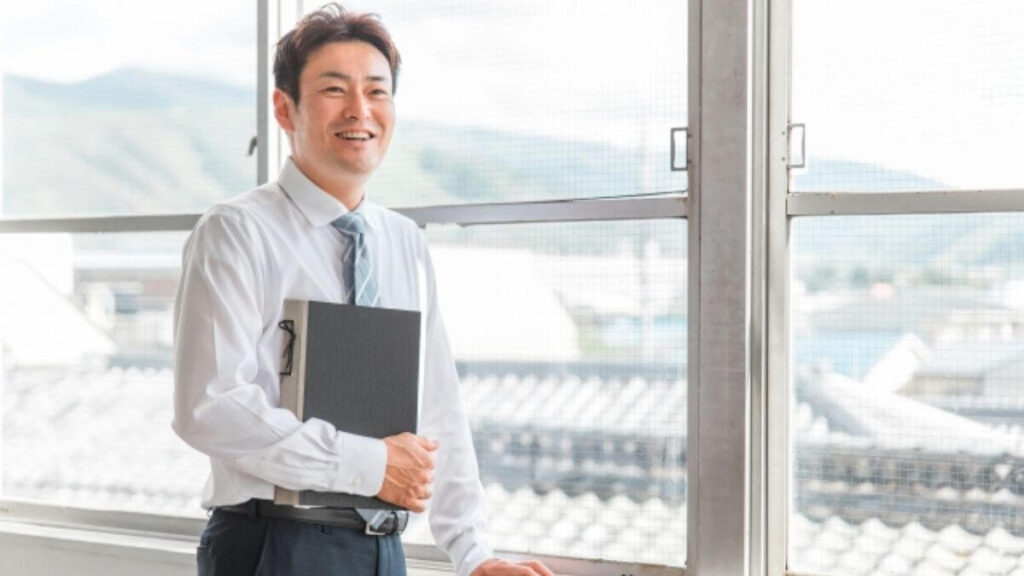 廊下で笑顔で会話をする男性のスクールカウンセラー