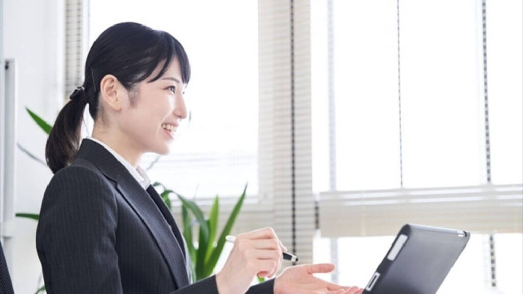 タブレットを使い笑顔で勉強するスーツ姿の女性