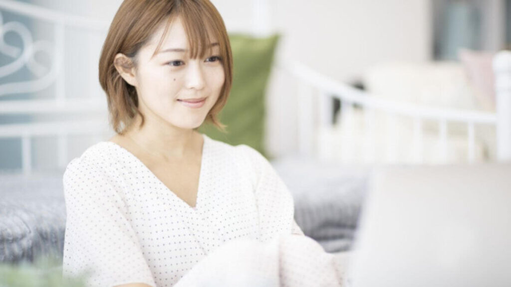 部屋でパソコンを使い勉強する若い女性