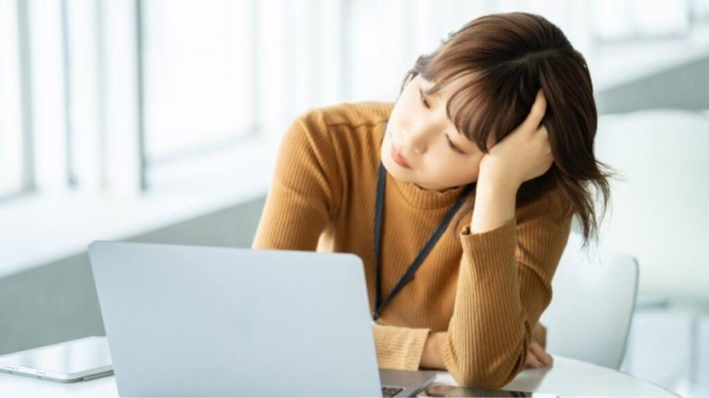 困った表情を浮かべながらパソコンを使って勉強する女性